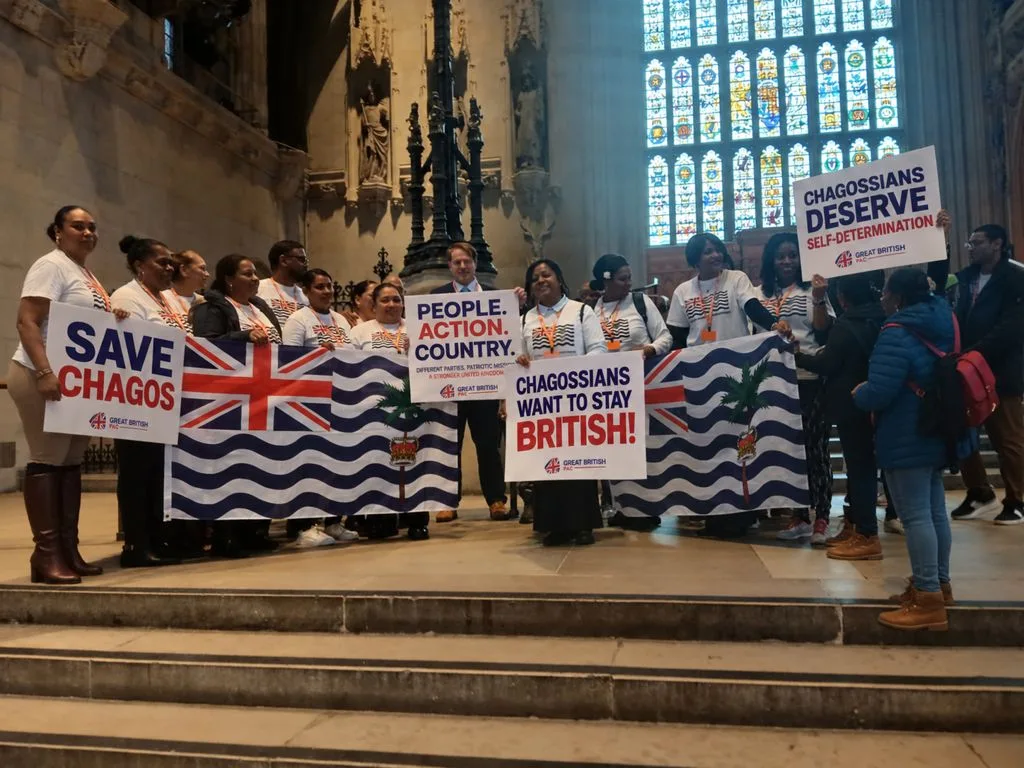 Chagossians and Great British PAC supporters in Westminster Hall with Save Chagos placards and British Indian Ocean Territory flags